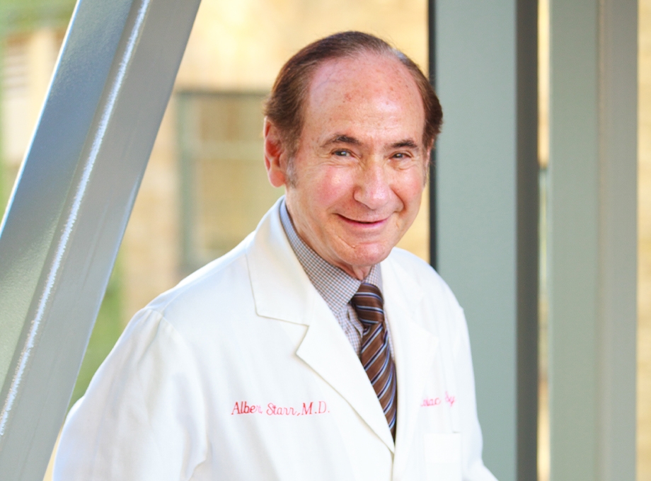 Albert Starr has short, sparse brown hair and was wearing a white coat, smiling at OHSU.