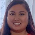 Alethea Barlowe has long brown hair and a red top, smiling.