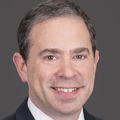 Daniel Herzig, M.D., M.B.A., FACS, FASCRS, has short black hair, wearing a suit and tie, smiling in a photo studio.
