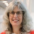Rebecca Spain, M.D., M.S.P.H., has gray hair, eye glasses and an orange sweater, smiling on the VA/OHSU bridge.