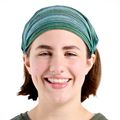 Molly Bell, diseñadora y paciente de Nike-OHSU Doernbecher Freestyle, lleva el pelo castaño cortado recogido con un pañuelo azul y verde y una blusa verde.