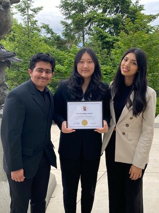 The BILLIES are three teens dresses in professional attire. The middle person is holding an award.