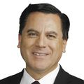 Rodrigo Lopez has short dark hair and a black suit with white shirt, and maroon tie, smiling.