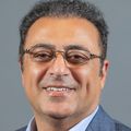 Shahrokh Shahidzadeh has short dark hair, eye glasses, and a gray suit, with blue shirt, smiling.