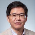 Hui Wu, Ph.D., M.S., has short straight black hair, eye glasses, and a beige suit with white shirt, smiling against a light blue background in a photo studio.