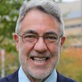 William Hersh, M.D., has short gray/black hair, eye glasses and wearing a suit and tie.