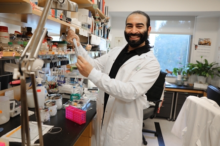 Karimi sonríe mientras sostiene un equipo en su laboratorio.