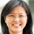 Jia has long straight black hair, eye glasses and a gray/blue blazer.