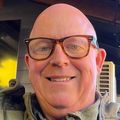 Shannon has no hair, eye glasses and smiling in a selfie photo.