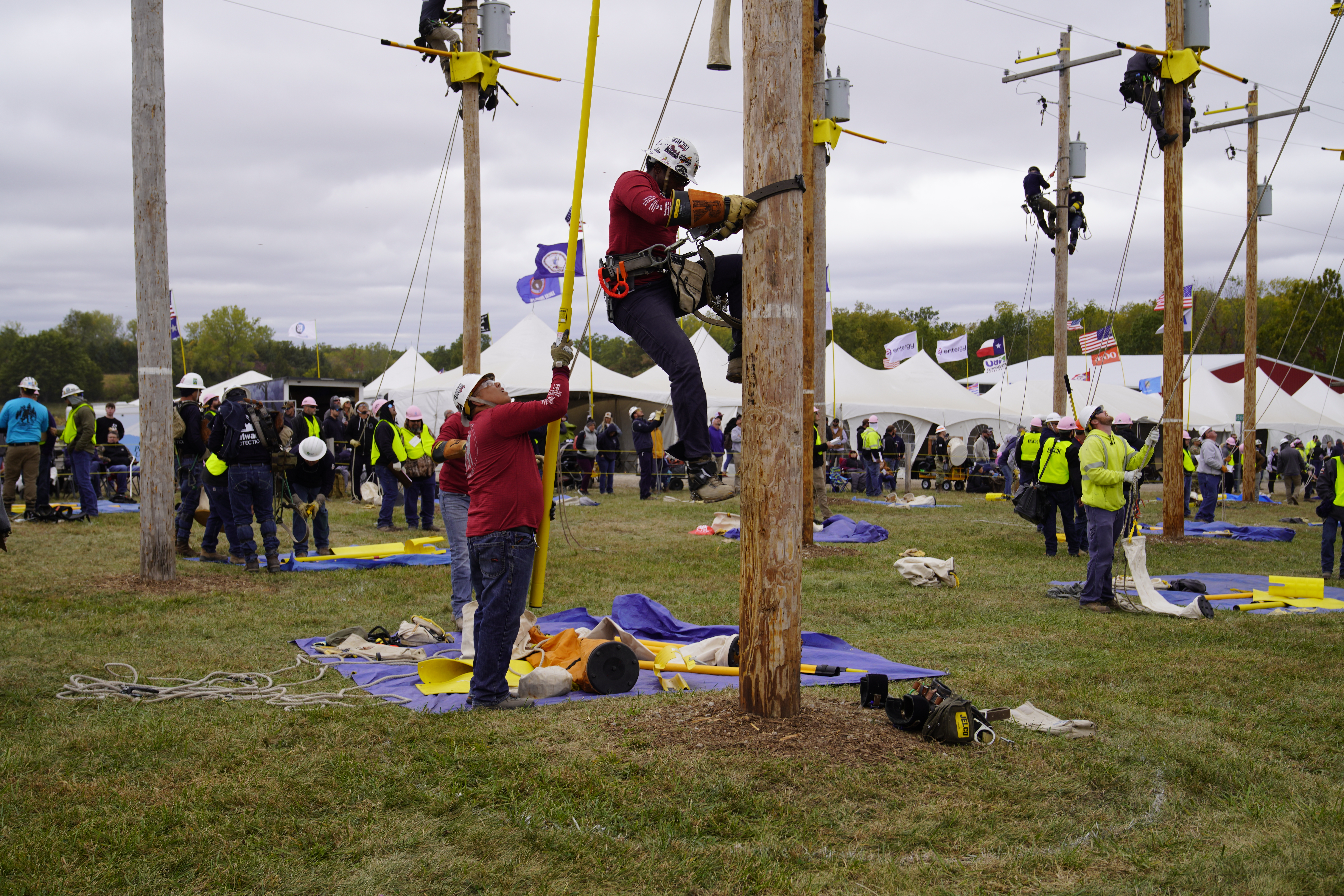 SCE lineworker Ramon Garcia holds a fiberglass extension pole as Wil Robinson begins his climb.