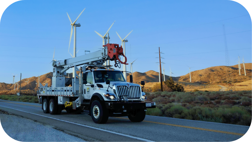Southern California Edison bucket truck driving on a road, near wind turbines