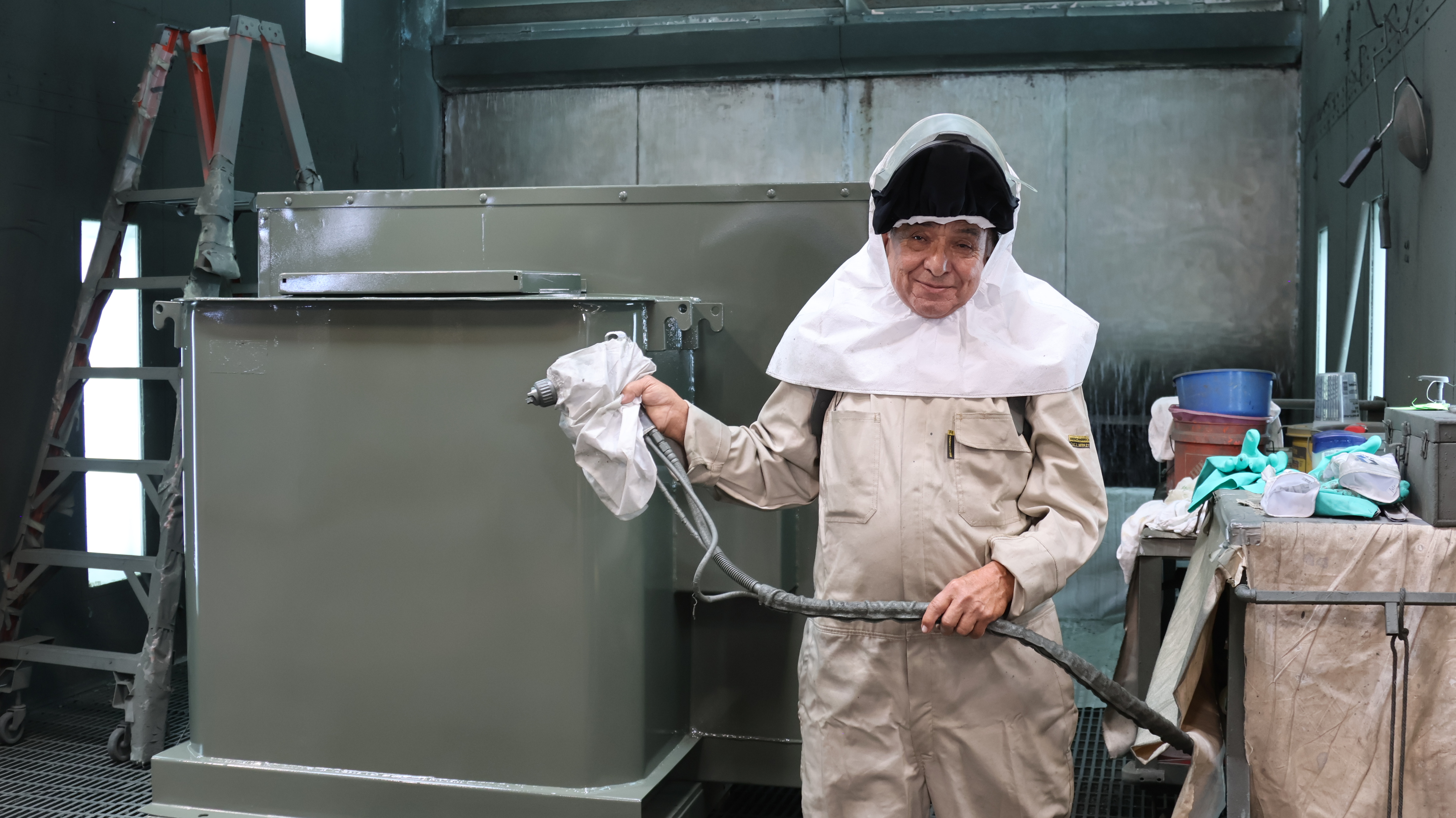 Before each paint session, Lopez gears up in a full air respirator suit for safety. 