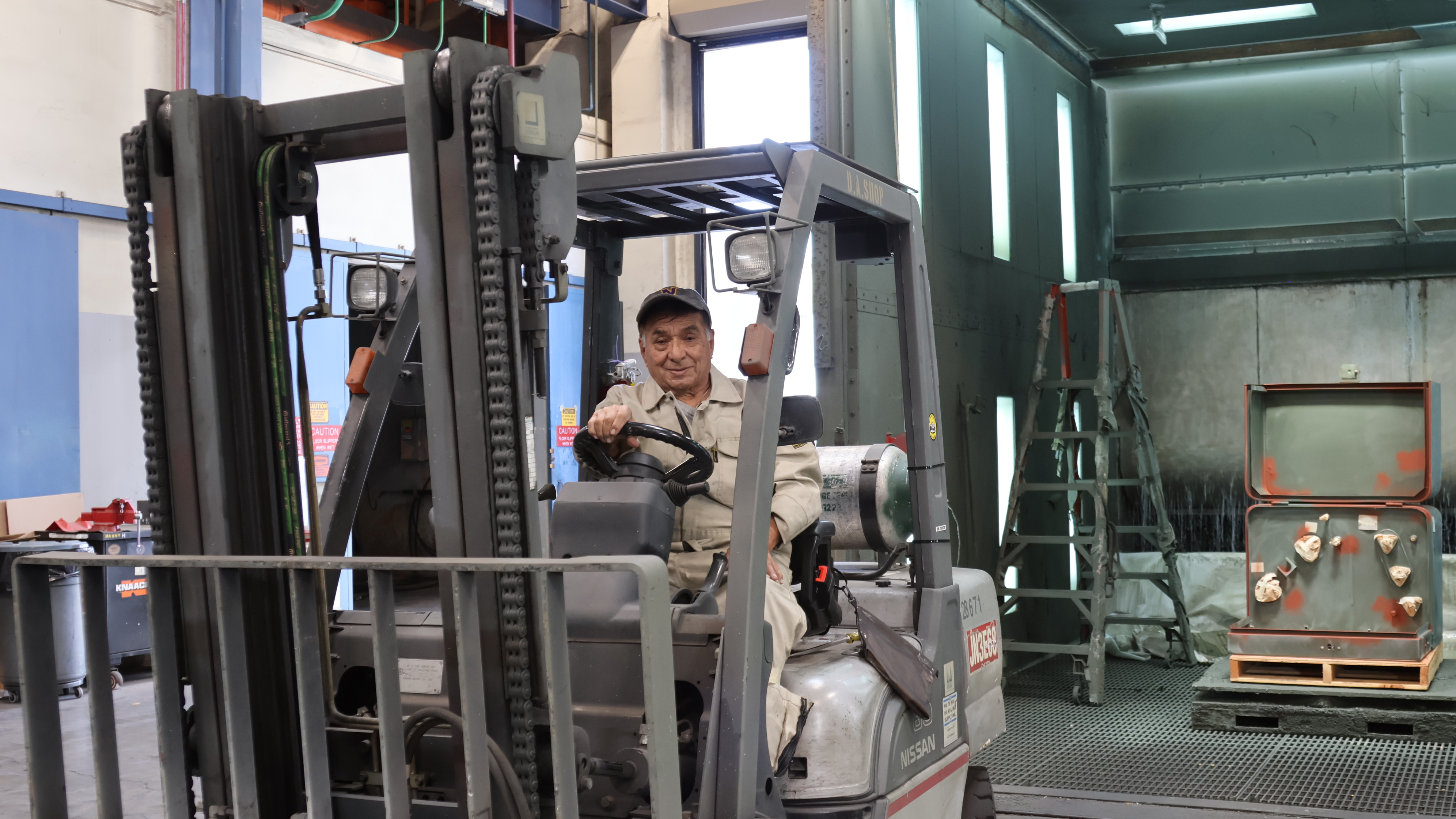 Maneuvering a forklift, Lopez moves transformers in and out of the paint booth.