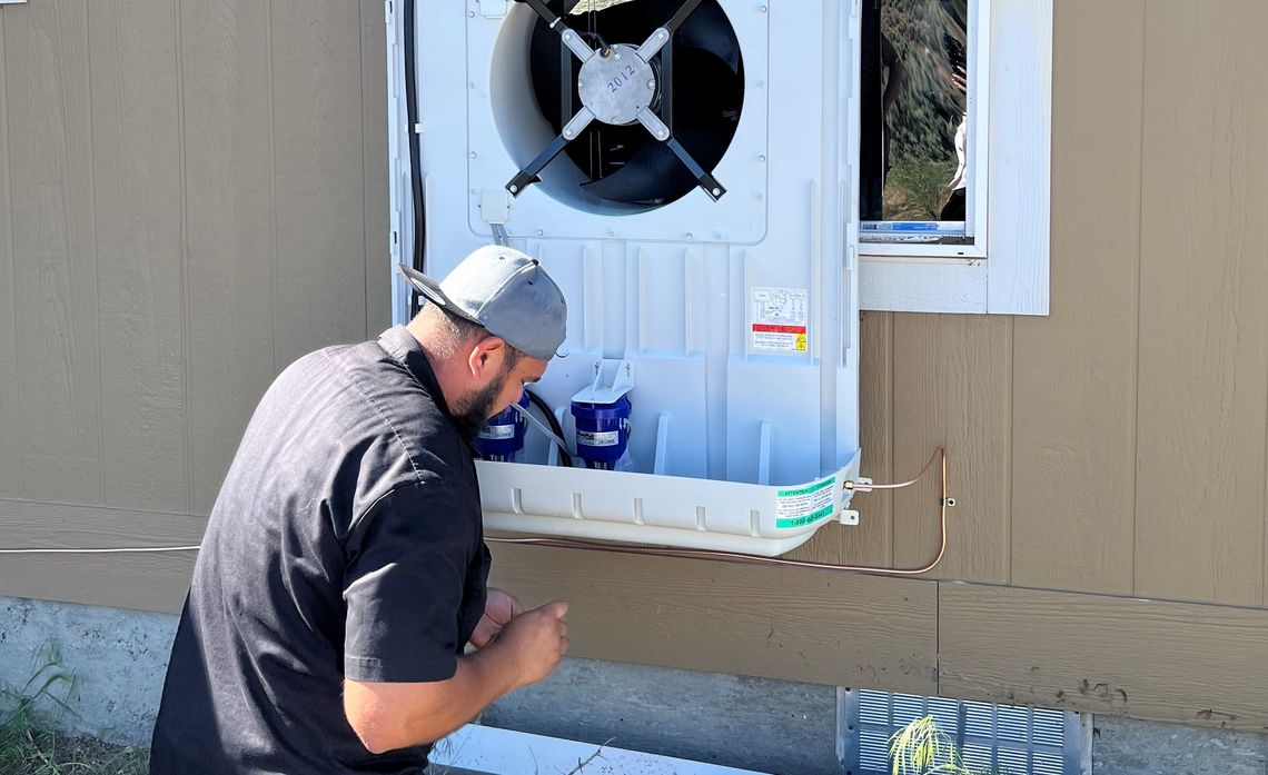 A contractor installs an energy‑efficient evaporative cooler in a Bridgeport Indian Colony home as part of SCE’s Energy Savings Assistance program.