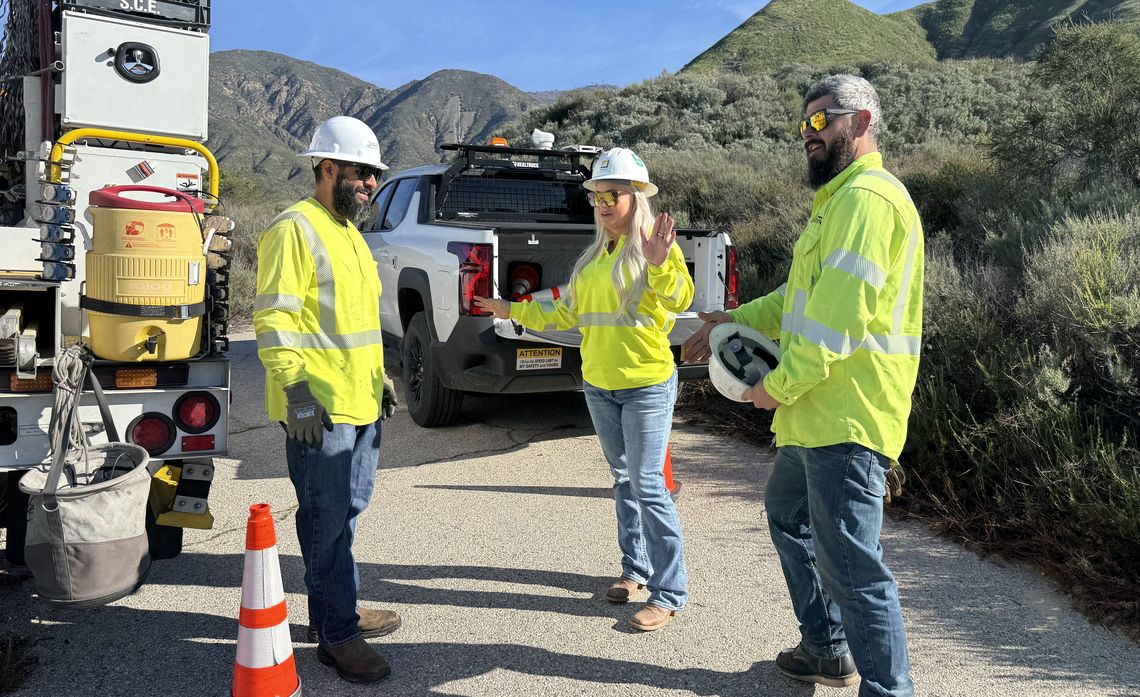 Alissa Osburn talks through the day’s work with a troubleman and lineworker, coordinating how to temporarily shut off power on sections of lines, so crews can safely replace a utility pole.