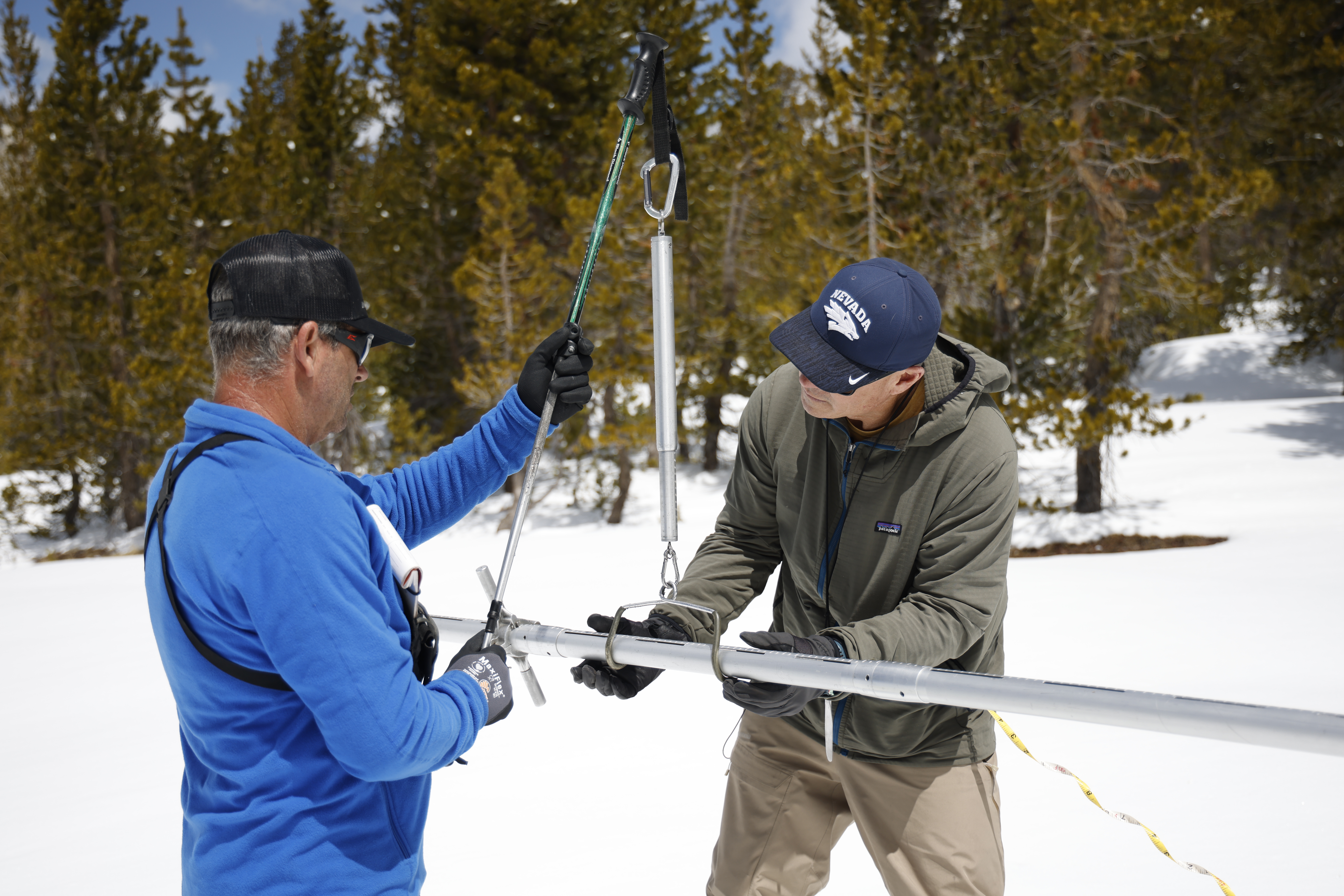 Working in sync, SCE Hydrographers Derrick Tito and Jeff Sherman weigh a freshly collected snow sample, a key step in calculating how much water is stored in the Sierra snowpack.