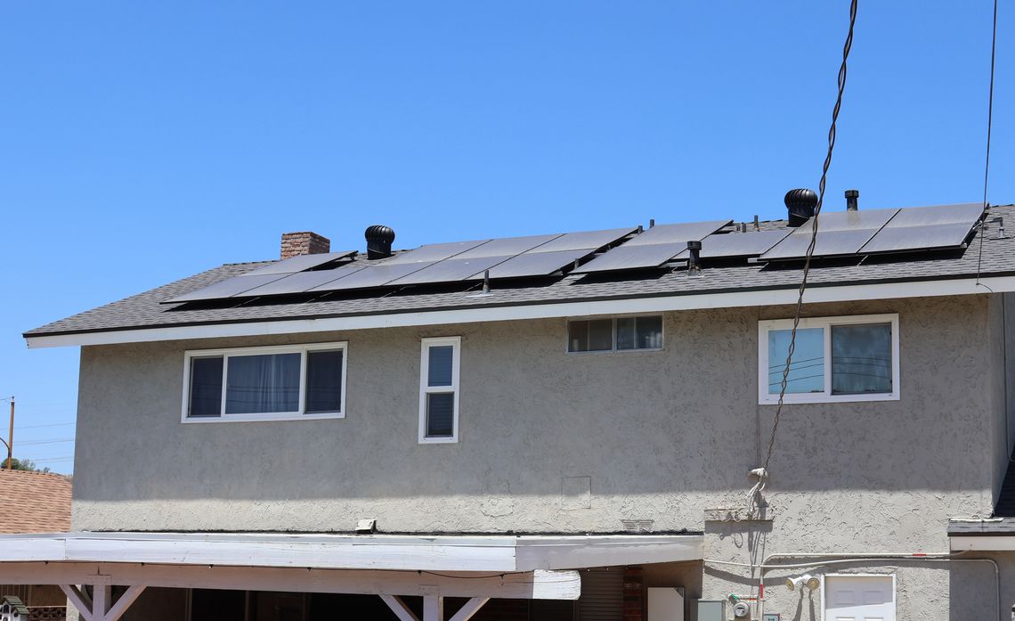 Two-story house with solar panels on the roof and a covered porch in the backyard.