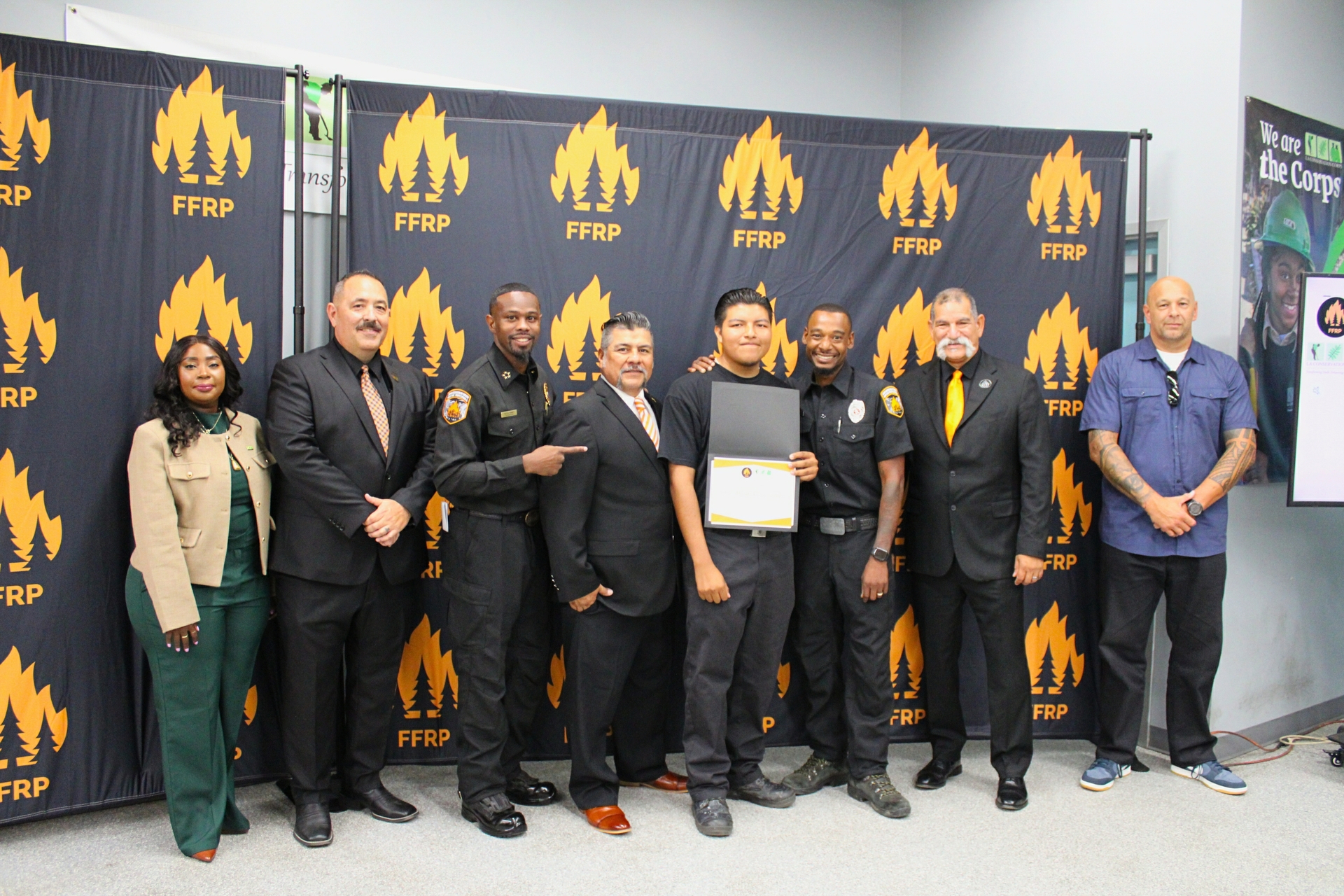 Julio Olivares (center) celebrates his graduation from the LA Conservation Corps wildland firefighter training program, joined by program leaders and first responders. 