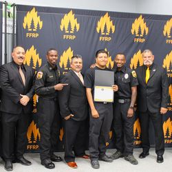 Julio Olivares (center) celebrates his graduation from the LA Conservation Corps wildland firefighter training program, joined by program leaders and first responders. 