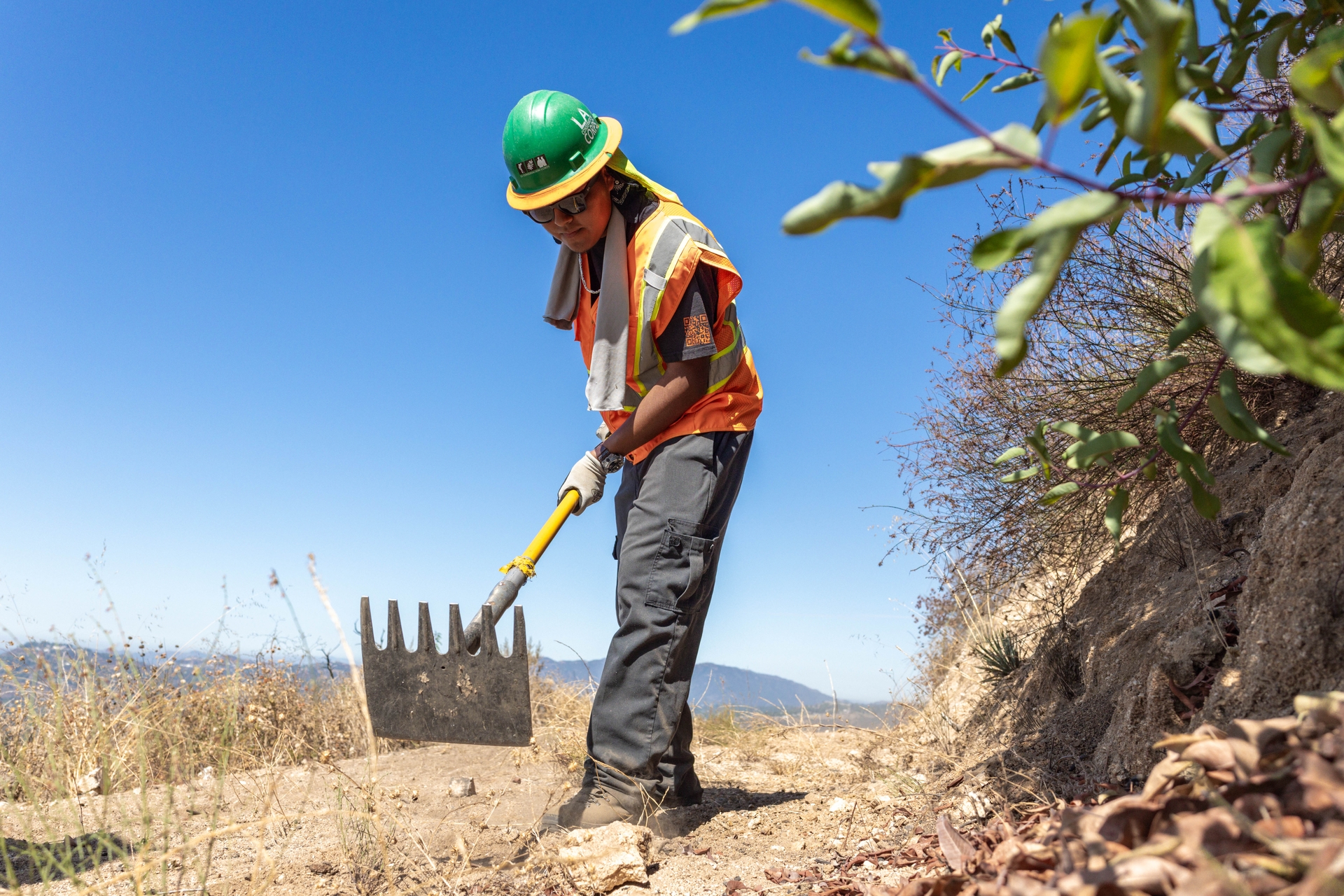 Julio Olivares, 20, clears brush along the fire-damaged Altadena Crest Trail as part of an LA Conservation Corps crew restoring the 5.5-mile path burned in the Eaton Fire.