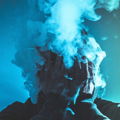Man with cloud of smoke on his face and blue background, Vaping