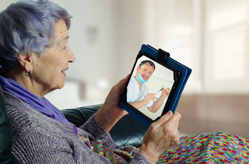 A nursing home resident safely discussing options with her dentist via teledentistry. Nursing home resident engaging in teledentistry