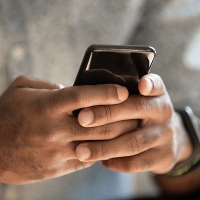 African man holding cellphone using applications, close up view