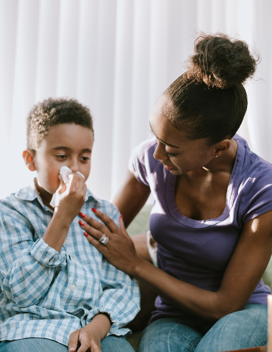 Sick child blows his nose and mother cares for him.
