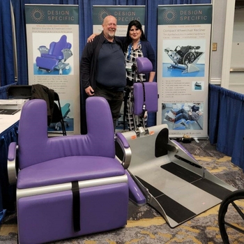 A purple bench is positioned next to a tilting ramp contraption that has a headrest attached to it. They are about the same width, so that the bench fits on top of the tilting contraption. There is a section cut out of the top of the bench backrest, where the headrest of the contraption can fit.