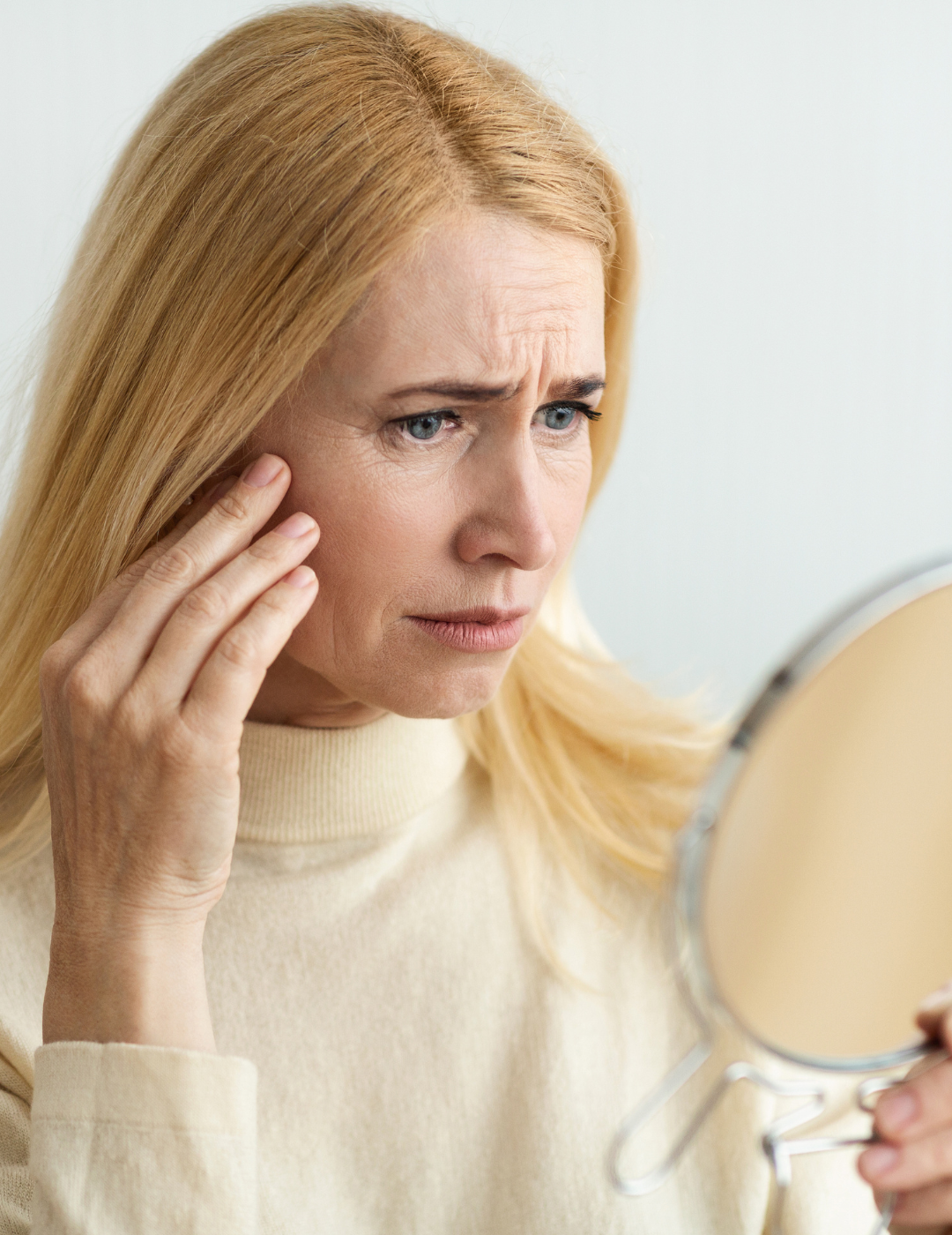 Woman looking at mirror at skin