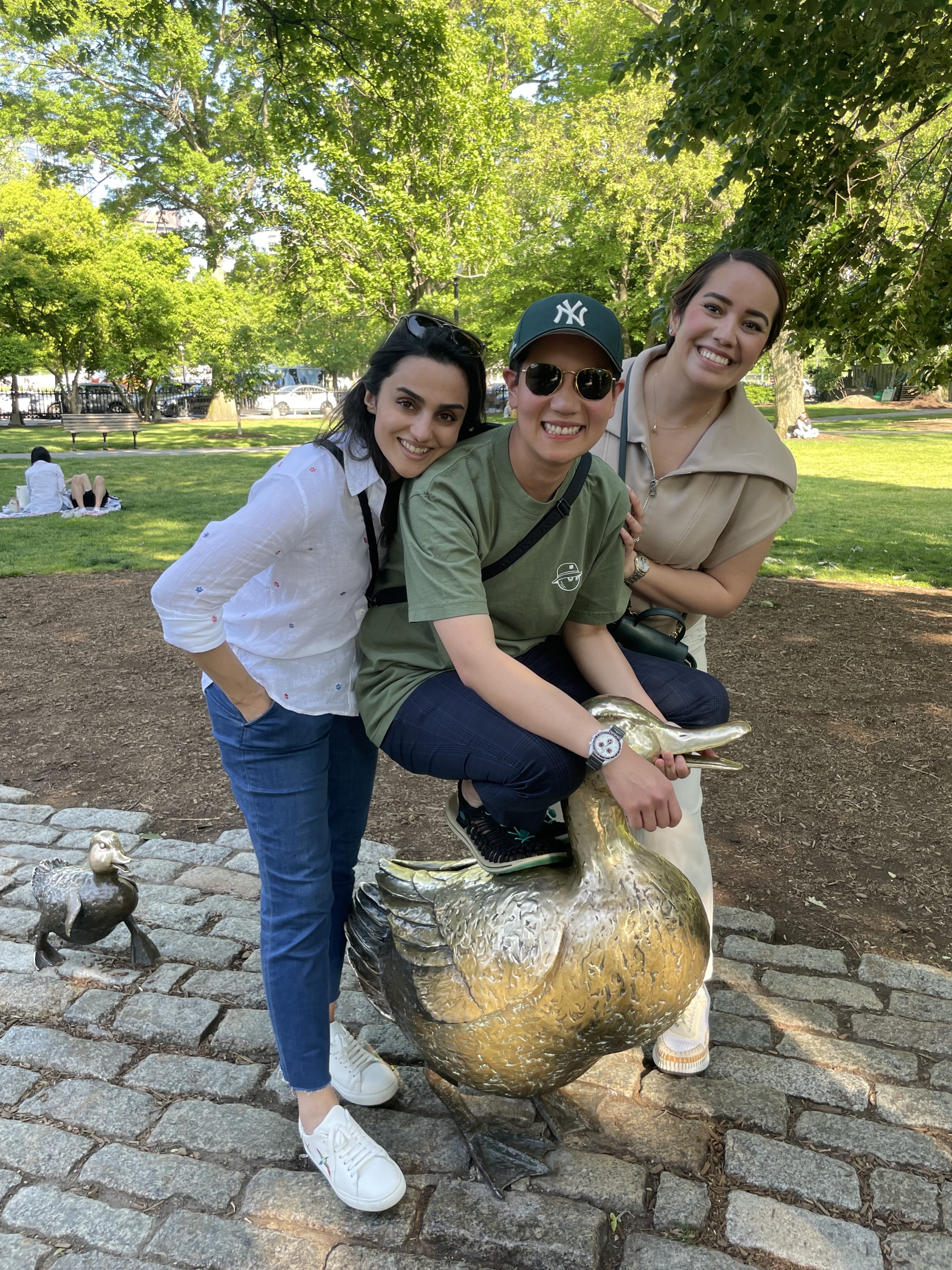 One person sits on a large duck statue while two others crowd in for a picture.