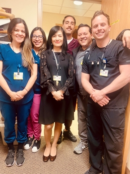 Five dental residents in scrubs pose with their mentor.