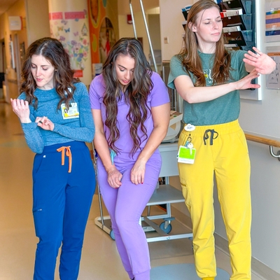 Three care providers pose like they are checking themselves for ticks: checking their arms, legs, sides.