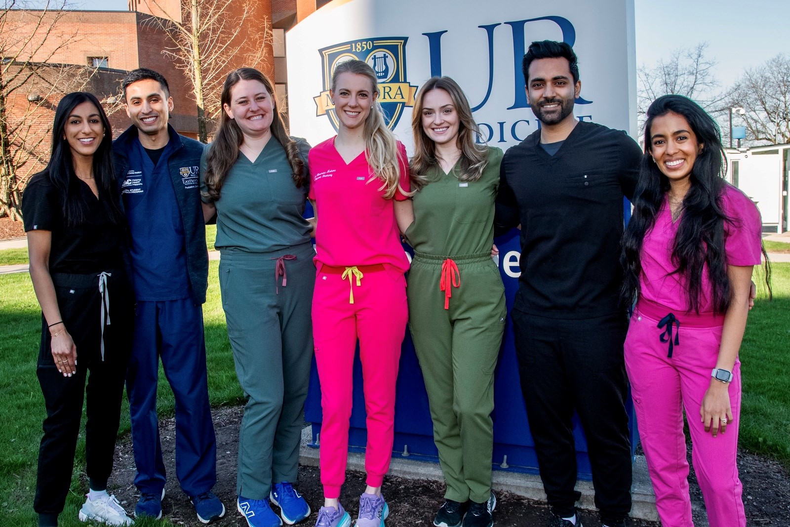 Seven people in scrubs stand in front of the Eastman Dental building