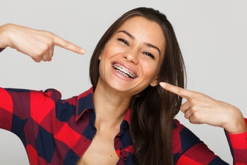 woman with braces smiling and pointing at them