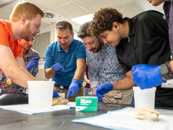 Pathologist Andrew Johnson, MD, (far left) points out anomalies on a diseased heart to  (left to right) Valodymir  Busch, Byron Behm, Future Deaf Scientists Co-Director Wyatte Hall, PhD, and Braulio Clark. Photo credit Erich Camping.
