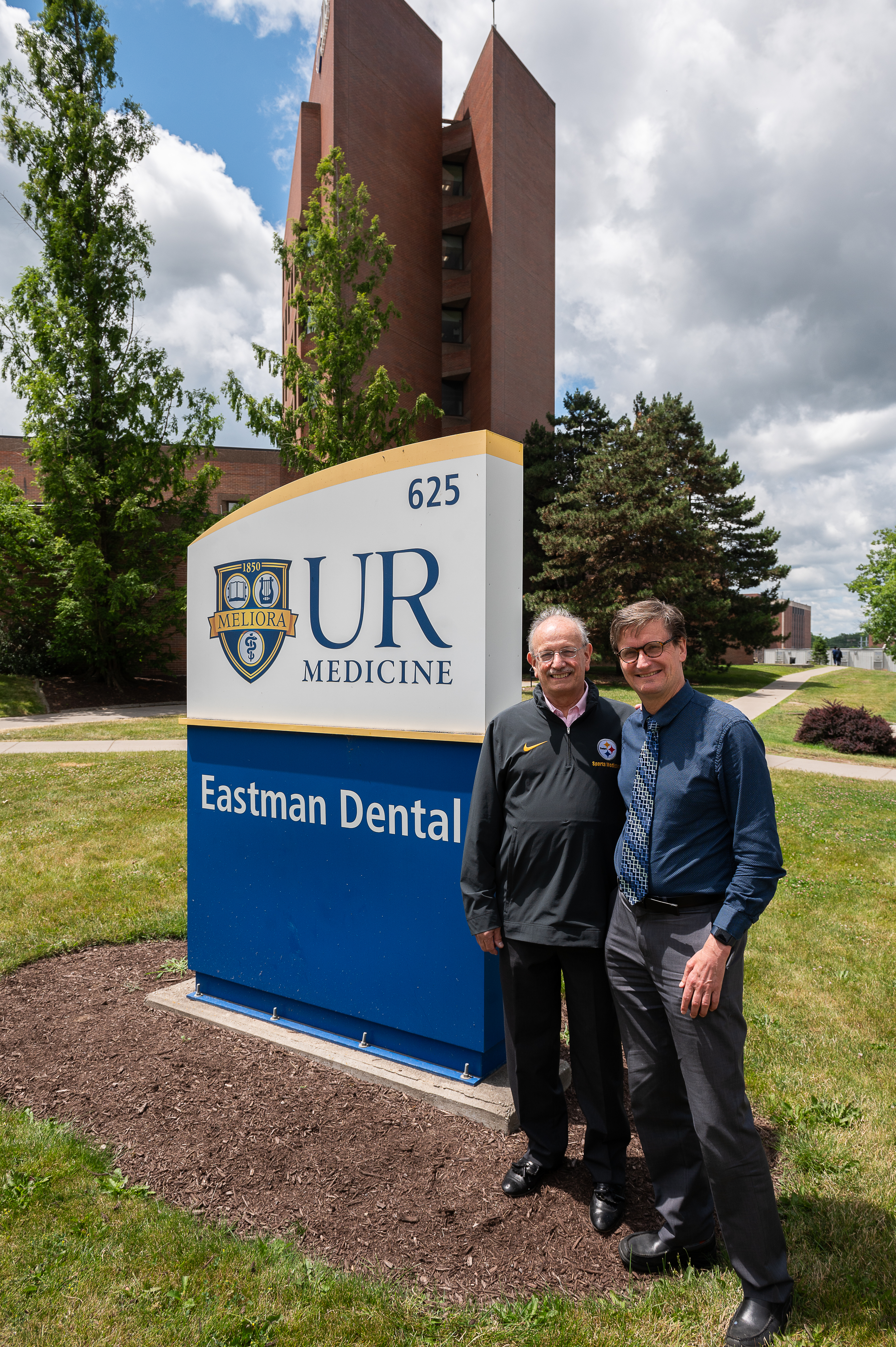 Dr. Gottlieb and Dr. Malmstrom standing in front of Eastman Dental sign outside