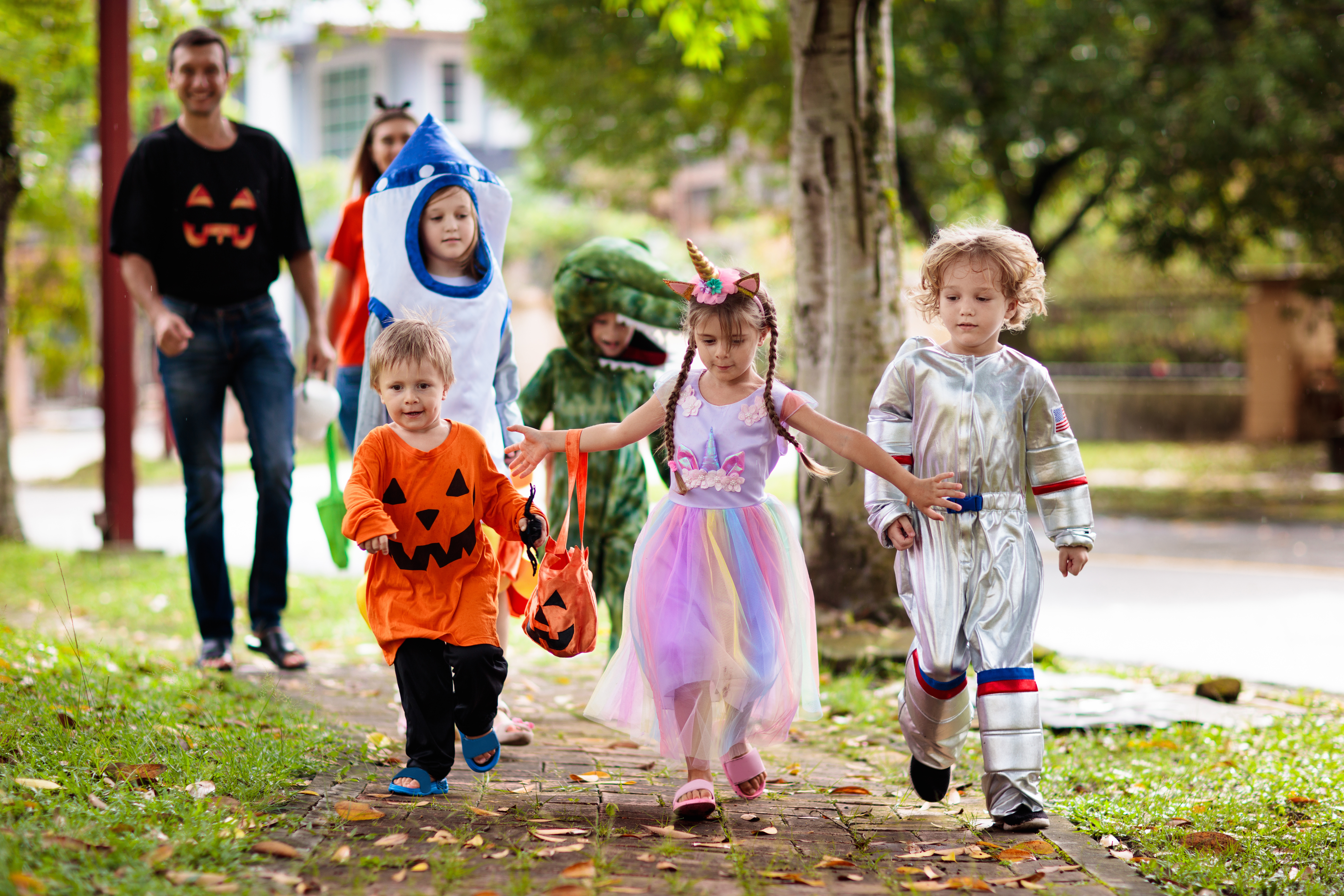 Children wearing costumes run down a sidewalk