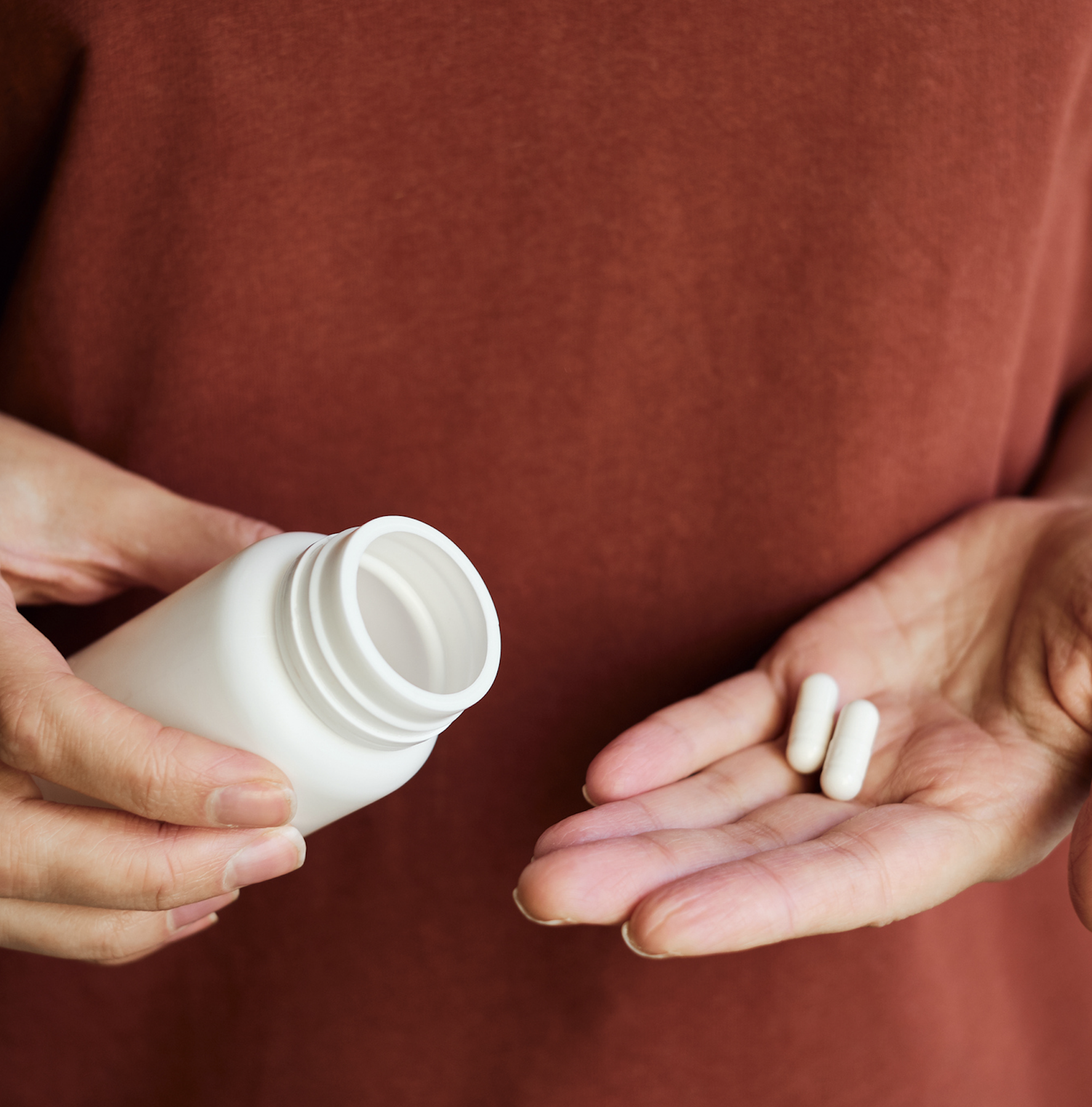 Person pours vitamins from bottle into hand