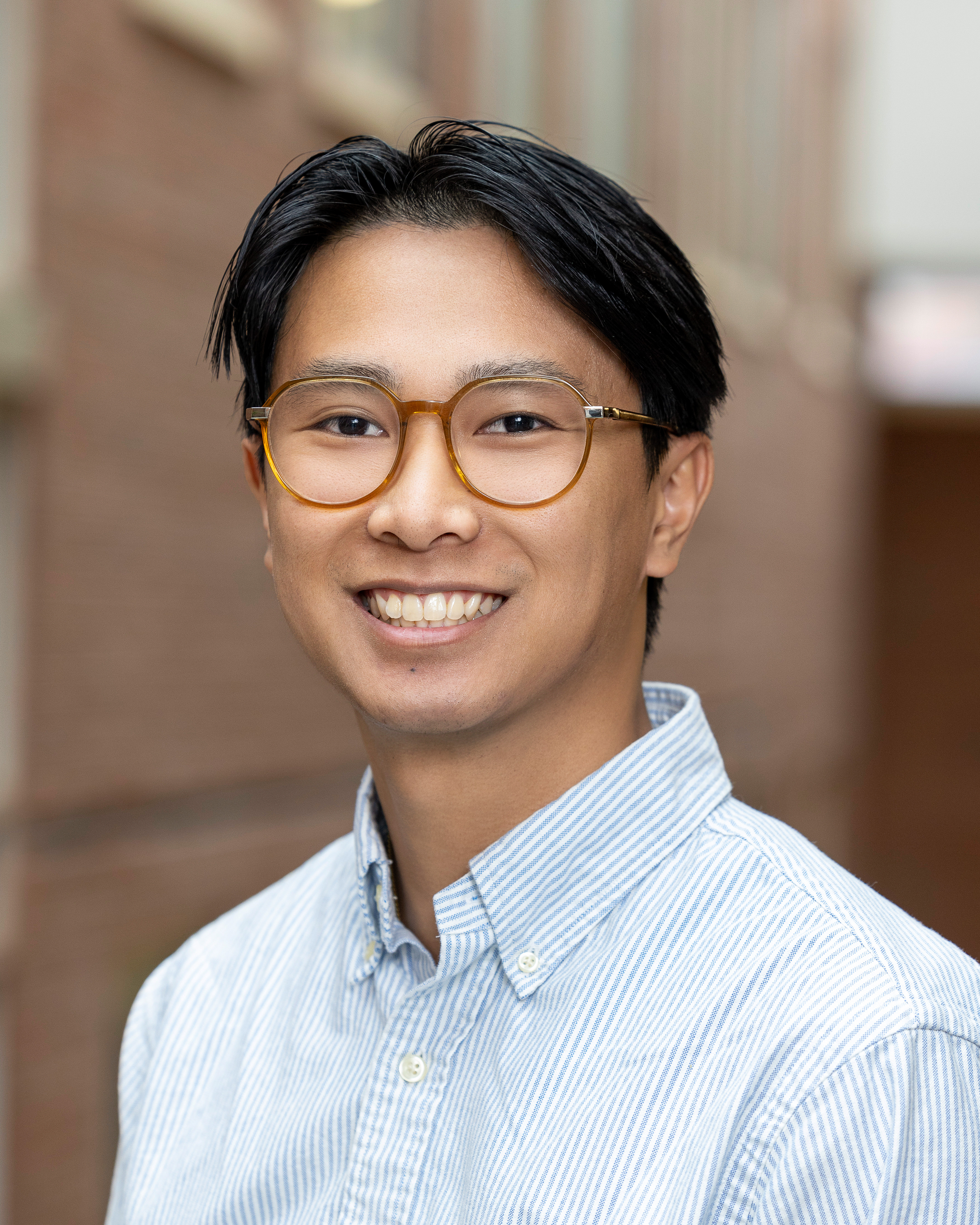 Aaron Huynh smiling with glasses, dark hair, and a collared shirt
