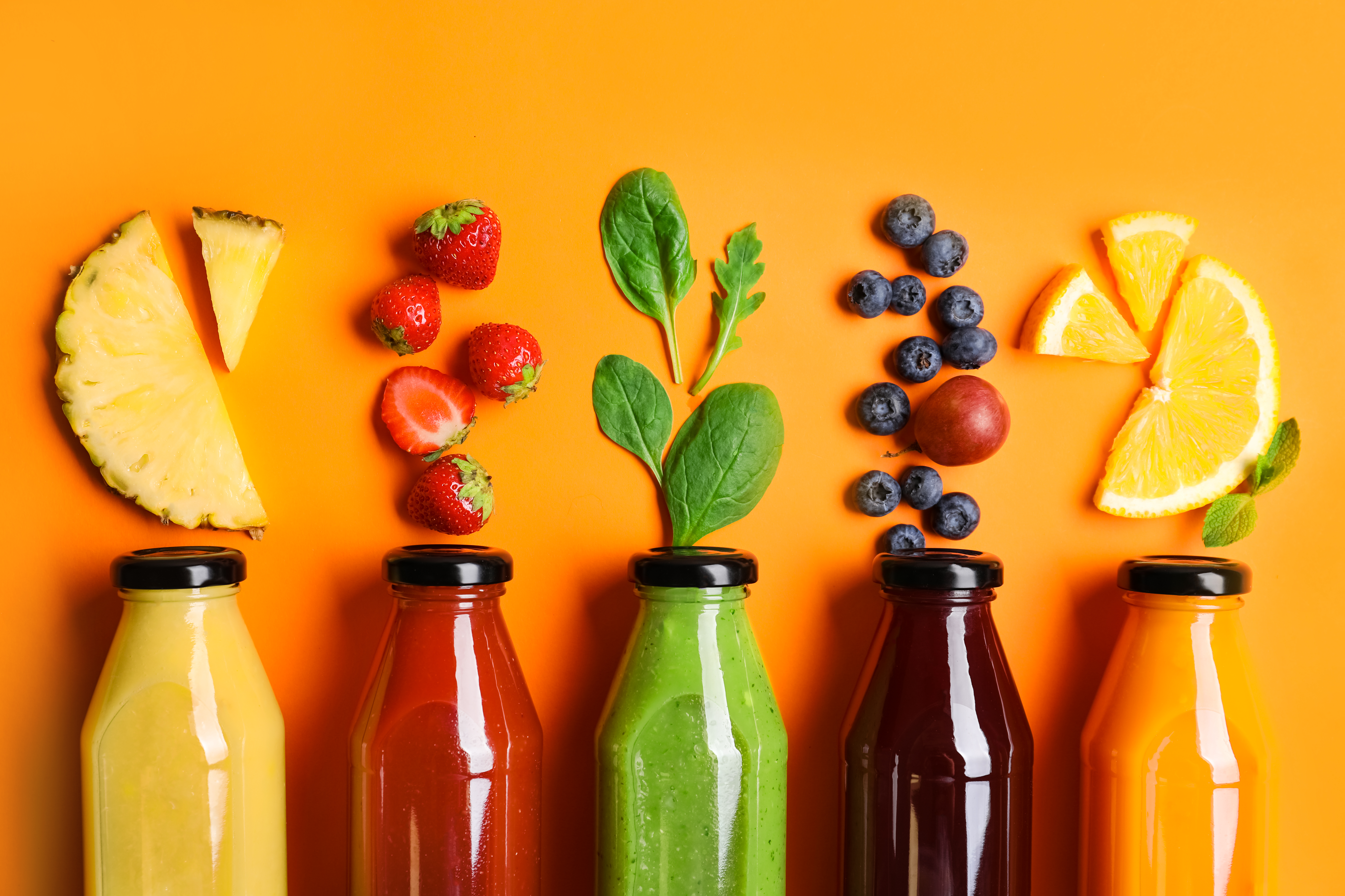 Four glass bottles with different colored juices