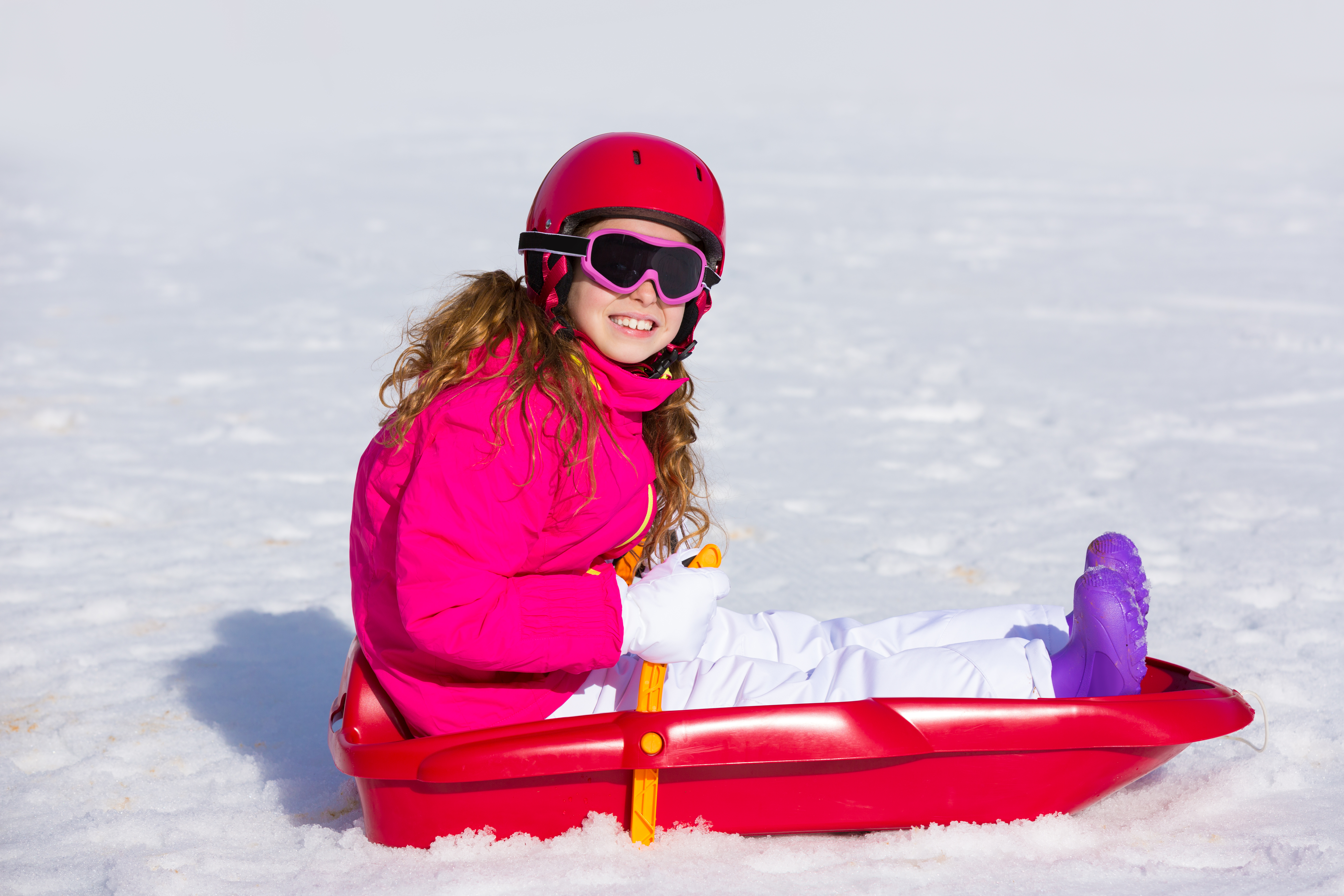 girl on steerable sled wearing helmet