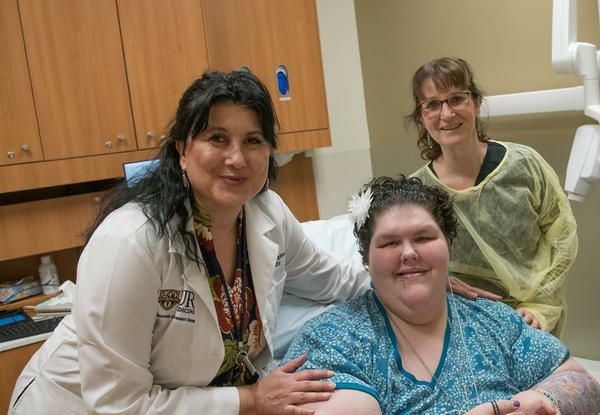 Dr. Stephens with patient with medically complex needs and dental assistant looking at camera