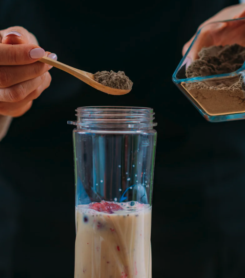 person adding protein powder to shake