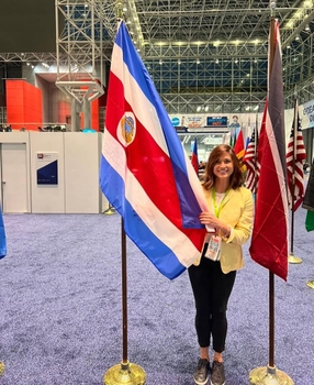 A woman poses next to a large Costa Rica flag.
