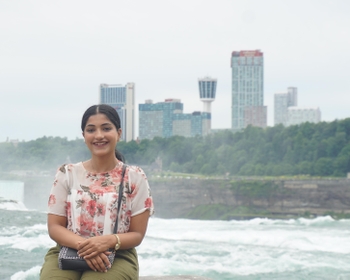 a woman stands in front of a river overlooking a city skyline