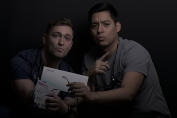 Two men in scrubs pose with various bone grafting materials in boxes.