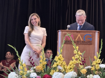 Dr. Gabriela Carranza smiles next to the podium and Dr. Eliav.