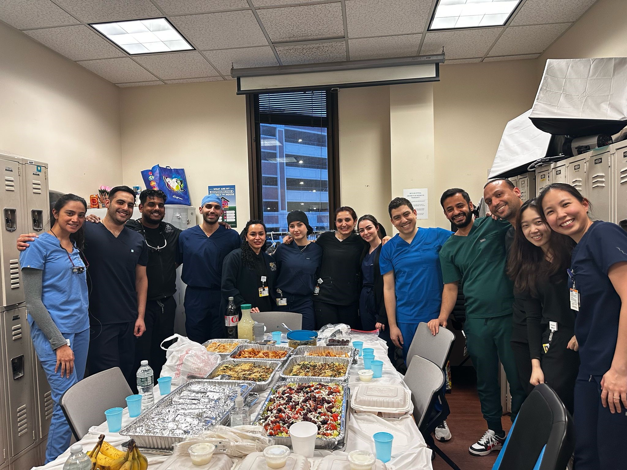 a group of people in scrubs stand around a table of food