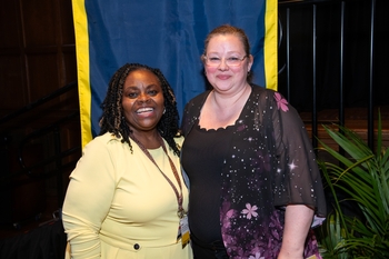 Carletta Carter and Melody Jones pose in front of a blue and gold banner.